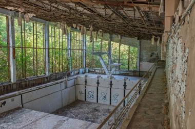 Abandoned indoor swimming pool shrouded in decay